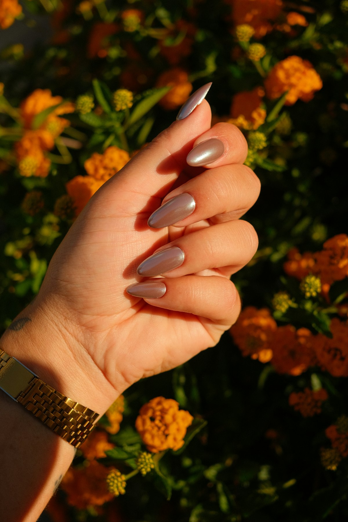Almond nude manicure holding a flower